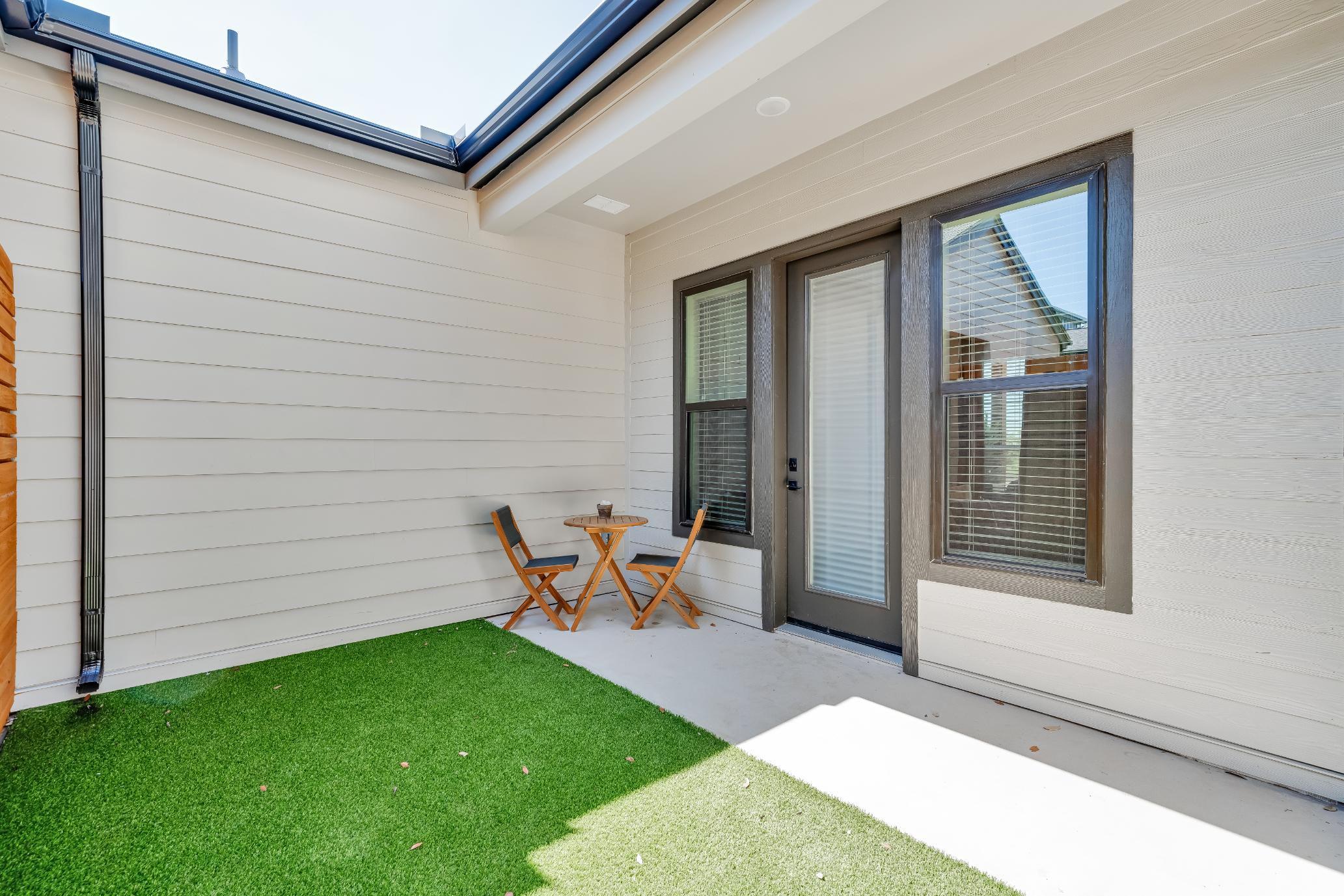 A private patio with a green lawn and table inside a home at The parcHAUS at Mustang Drive