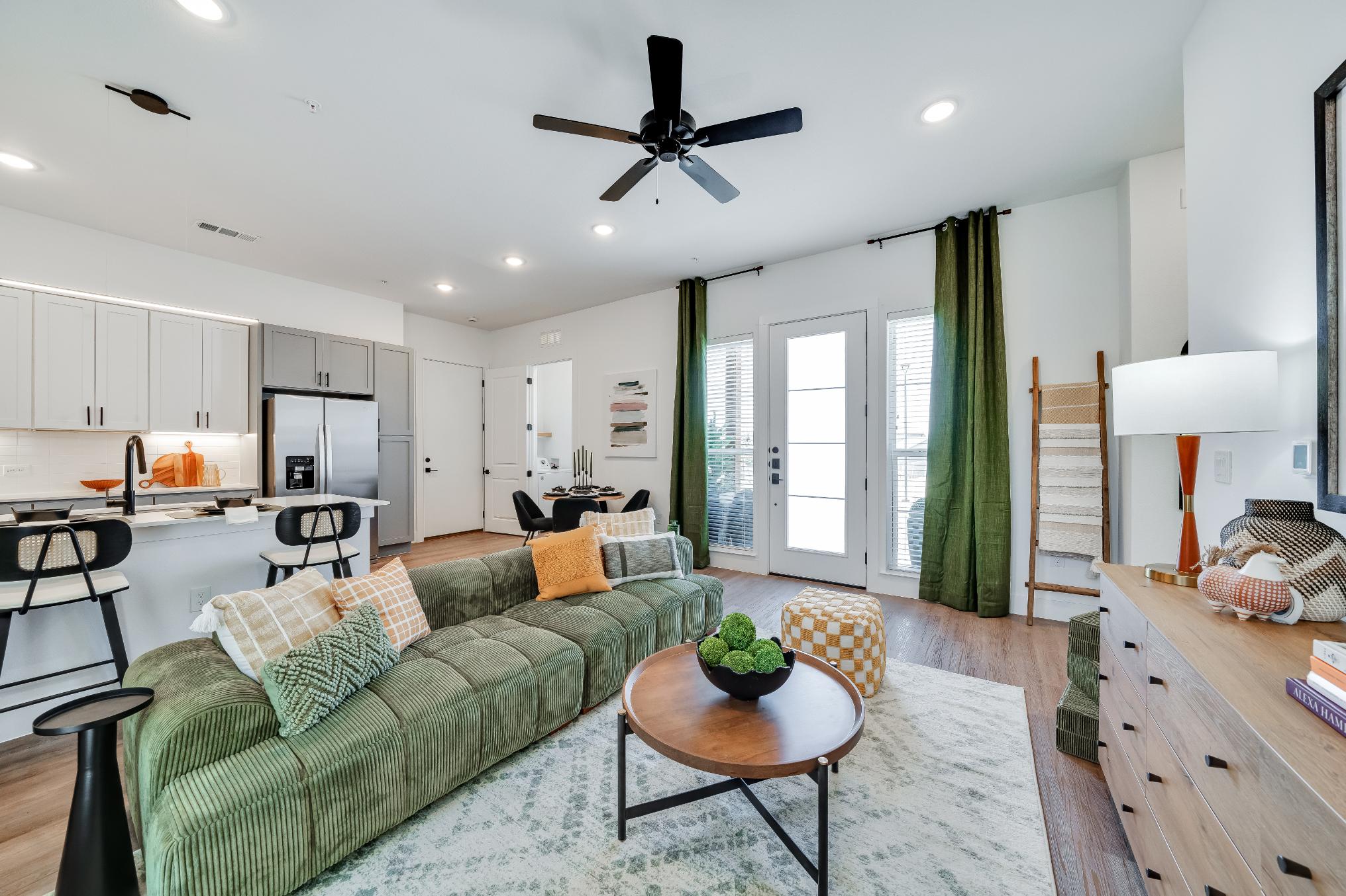 Furnished home living room with a ceiling fan and ample lighting inside a unit at The parcHAUS at Mustang Drive
