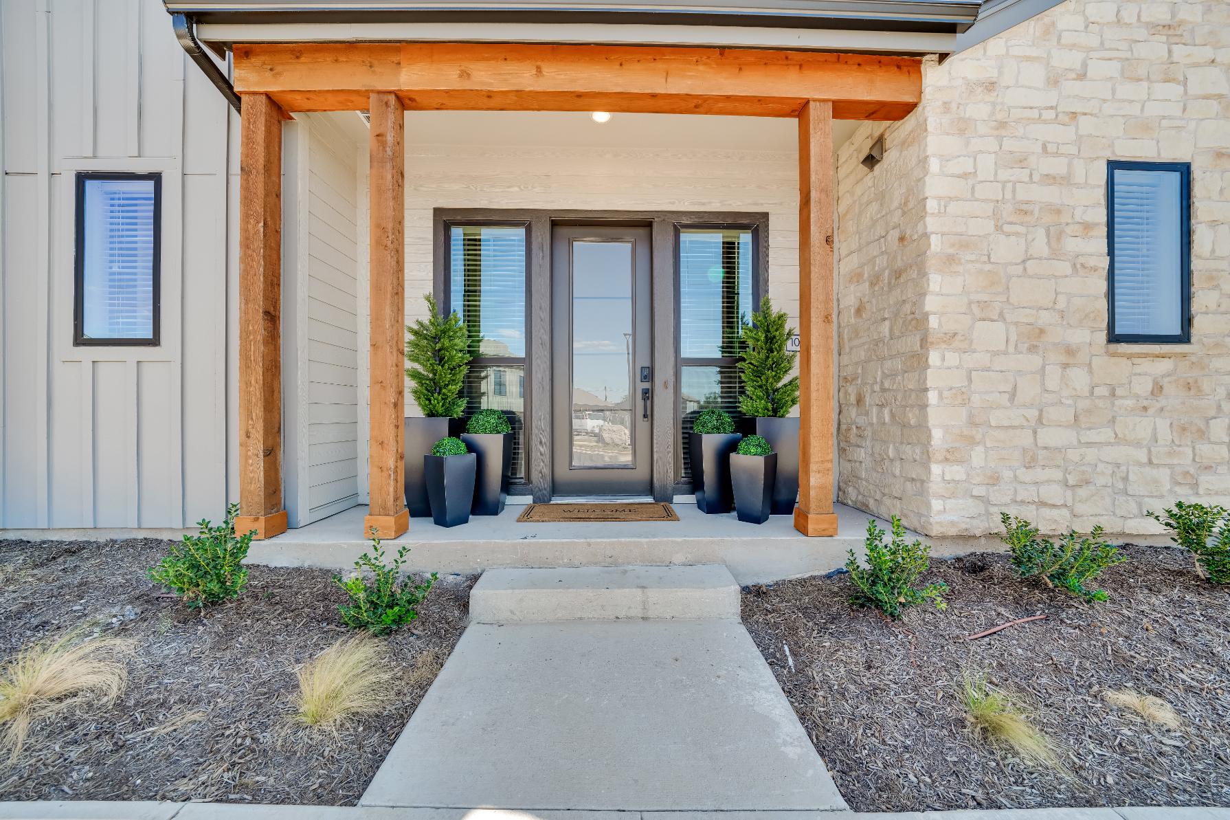 Exterior view of a front entrance of a home with a large potted plant at The parcHAUS at Mustang Drive