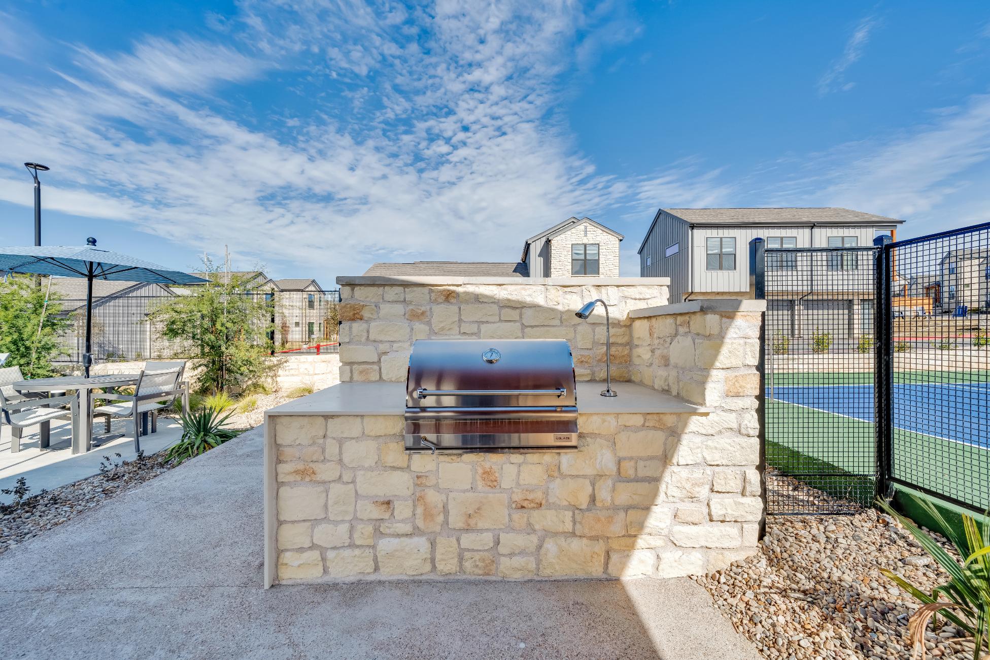 a barbecue grill and a tennis court in front of a house at The parcHAUS at Mustang Drive